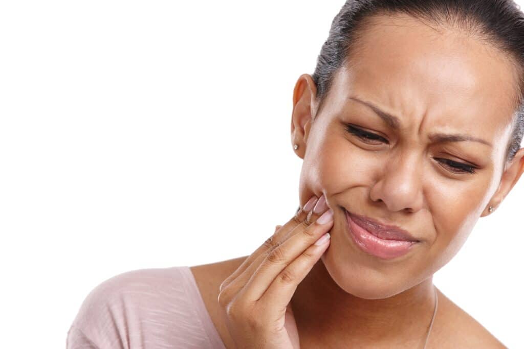 Woman holding her mouth in pain after wisdom teeth surgery, seeking a restorative dentist in Jackson.