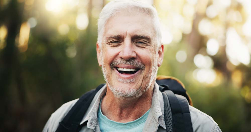 Smiling older man outdoors with healthy teeth, representing lGone Grafting in Jackson, WY