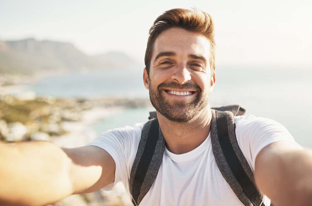 Smiling man taking selfie with bright, healthy teeth after Cosmetic Dentistry