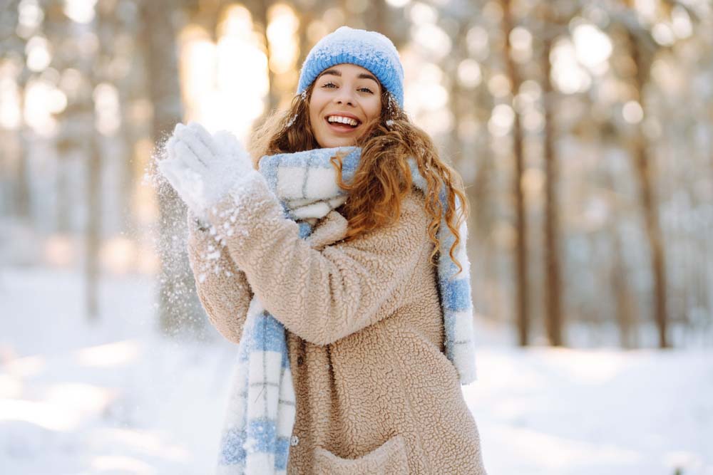 Smiling woman outdoors in winter, showing healthy teeth after dental Crowns