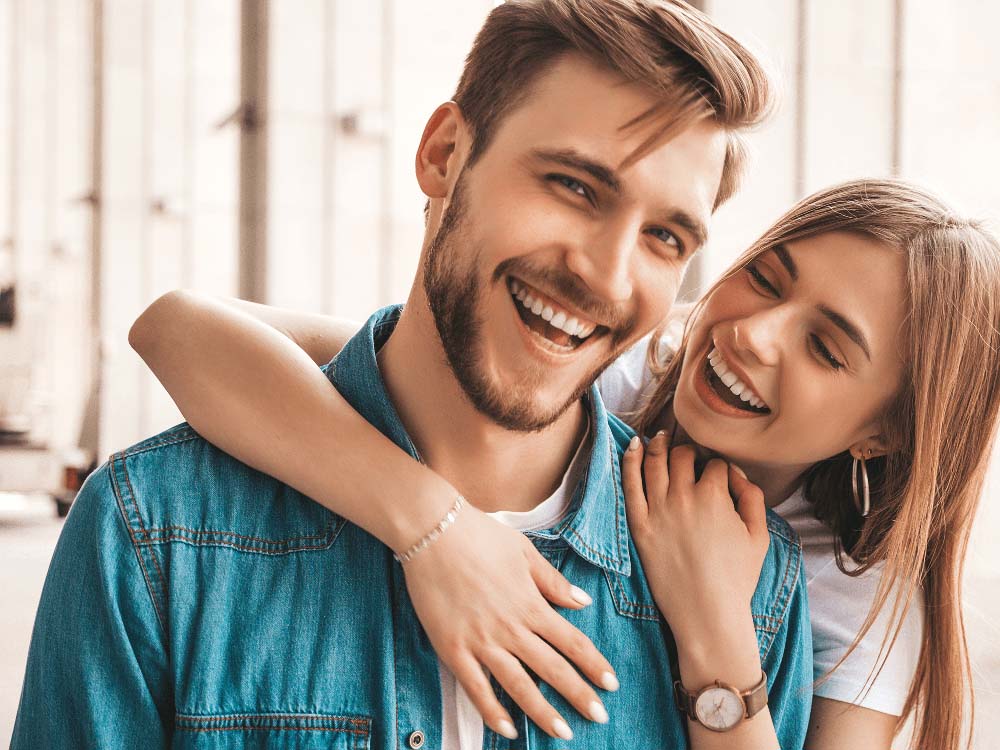 Happy couple with bright smiles, showcasing results of cosmetic dental treatments