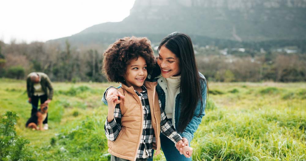 Mother and child smiling outdoors, representing family dental care services