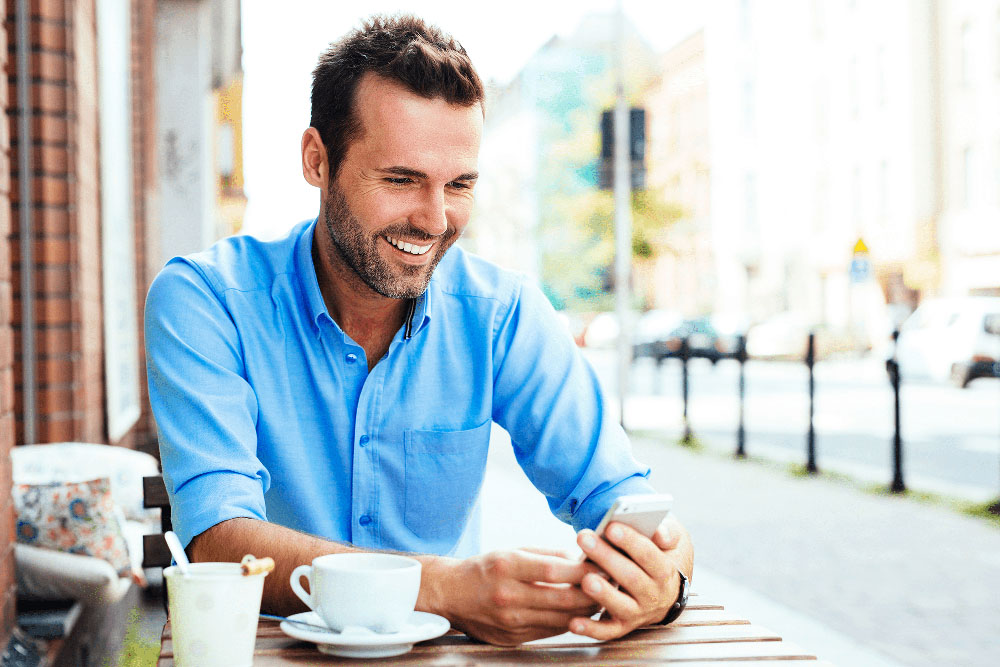 Man smiling at café with bright teeth, highlighting cosmetic dentistry results
