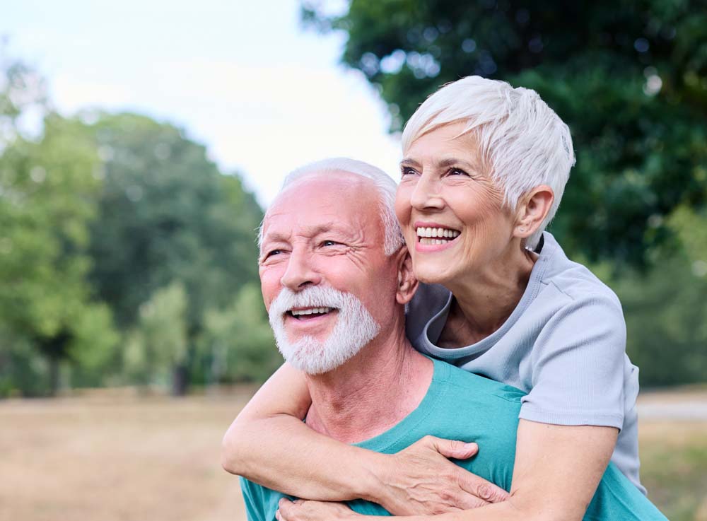 Active senior couple smiling outdoors, representing oral care and Periodontics
