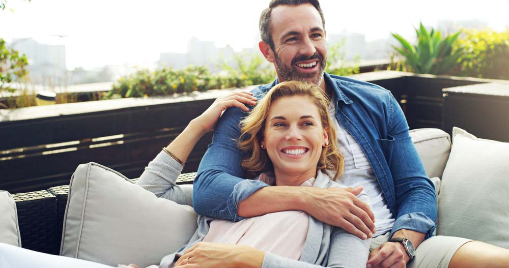 Smiling couple relaxing together, representing cosmetic and TMD Therapy results